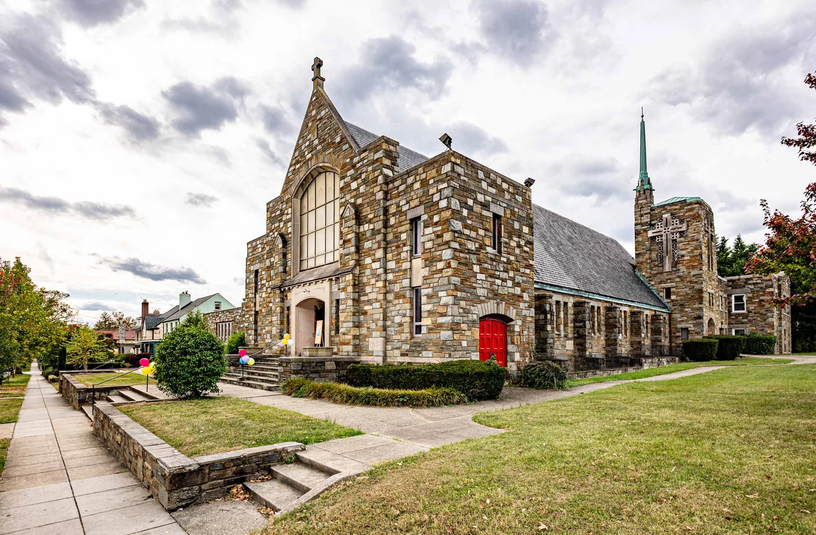 Northminster Presbyterian Church on Alaska Ave NW: stone facade, red arched door, and green copper spire